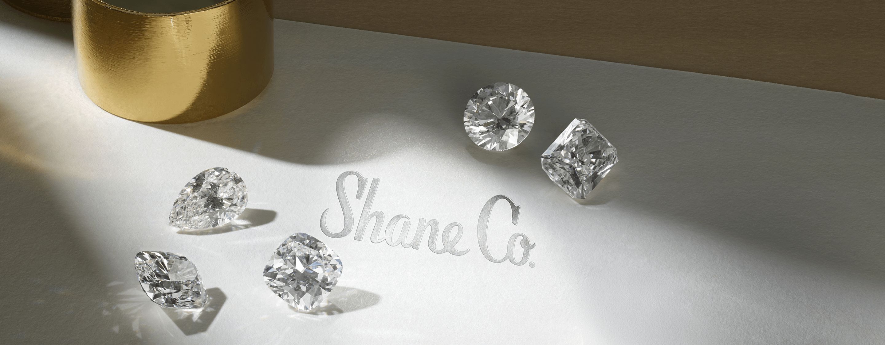 Loose diamonds of different shapes on a Shane Co branded inspection sheet.