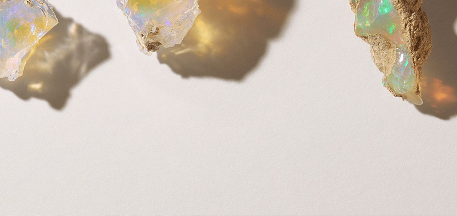 Three uncut opal gemstones on a pale background