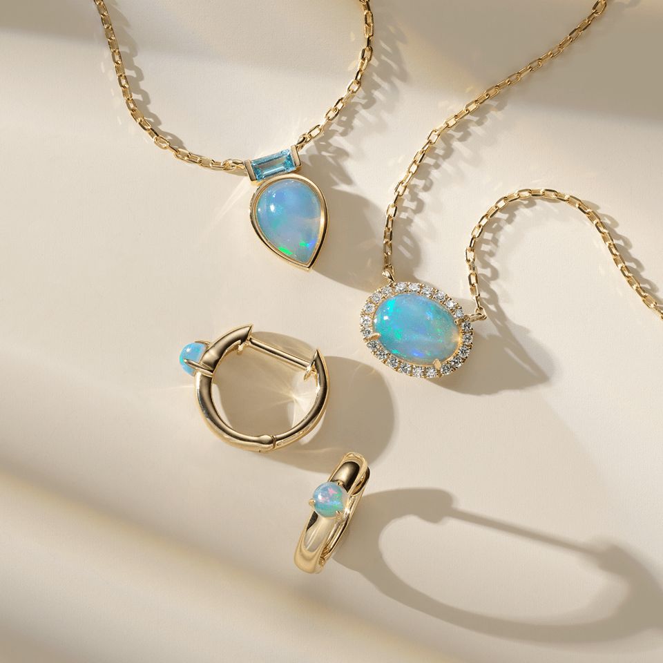 Two opal pendants next to a pair or opal hoop earrings