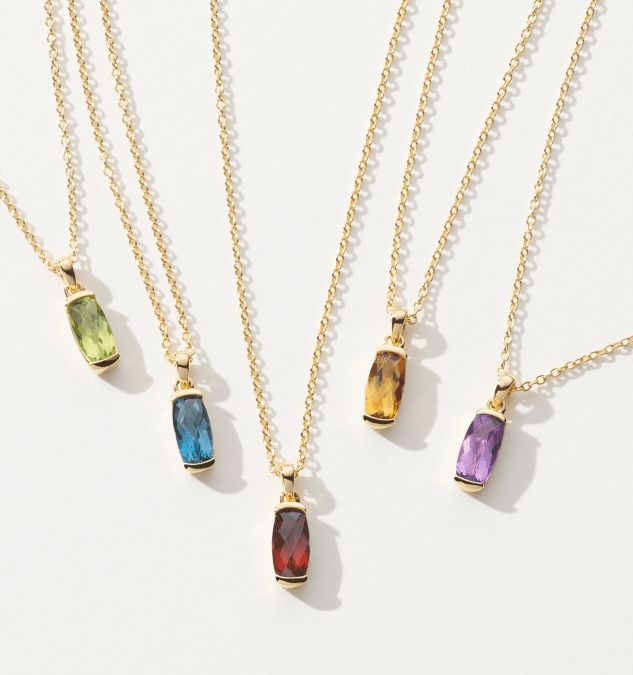 Five gemstone pendants with different colored gemstones.