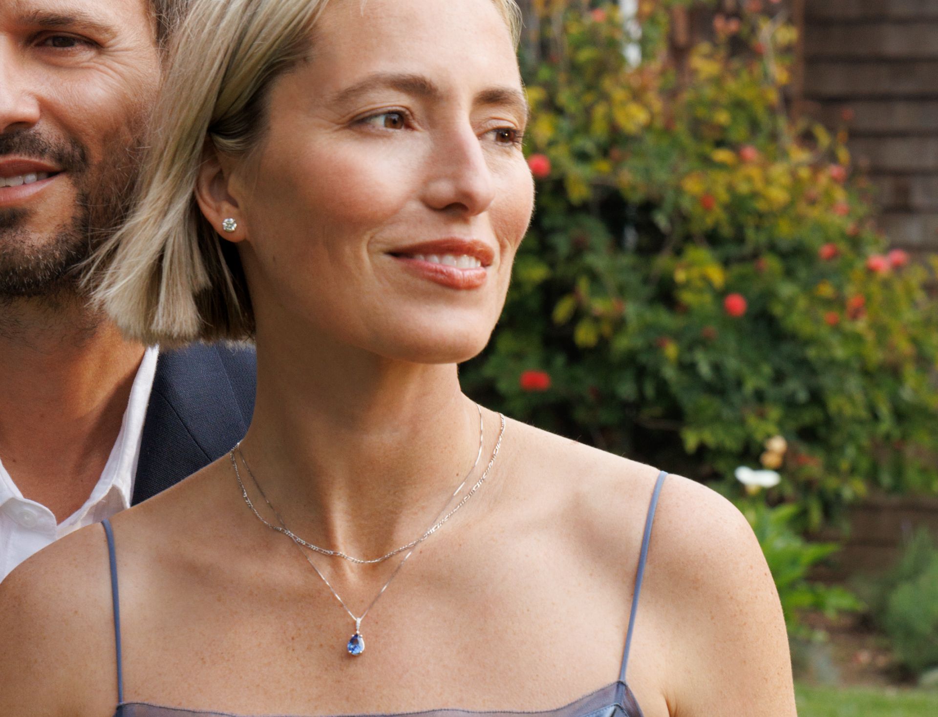 A woman wearing a sapphire and diamond necklace and an image of a sapphire pendant surrounded by other colored sapphires.