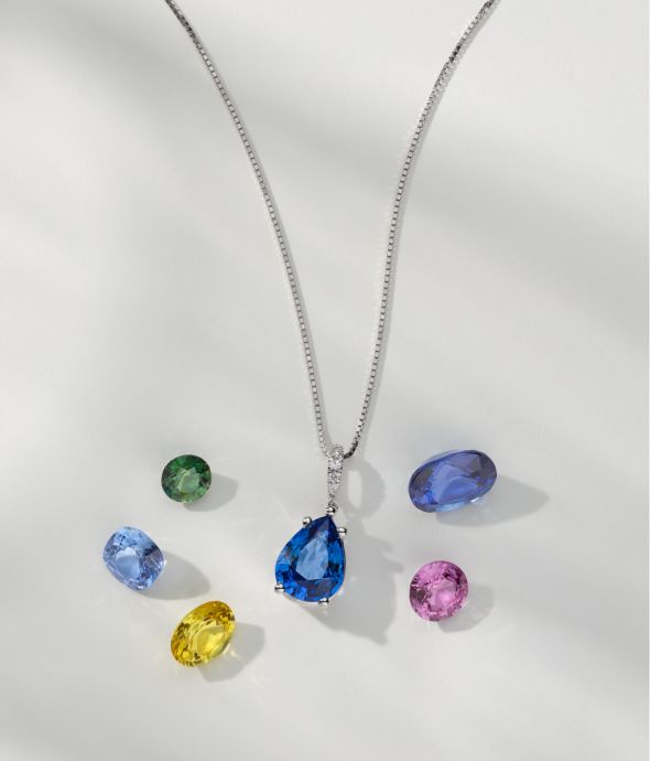 A sapphire pendant surrounded by loose colored sapphires.