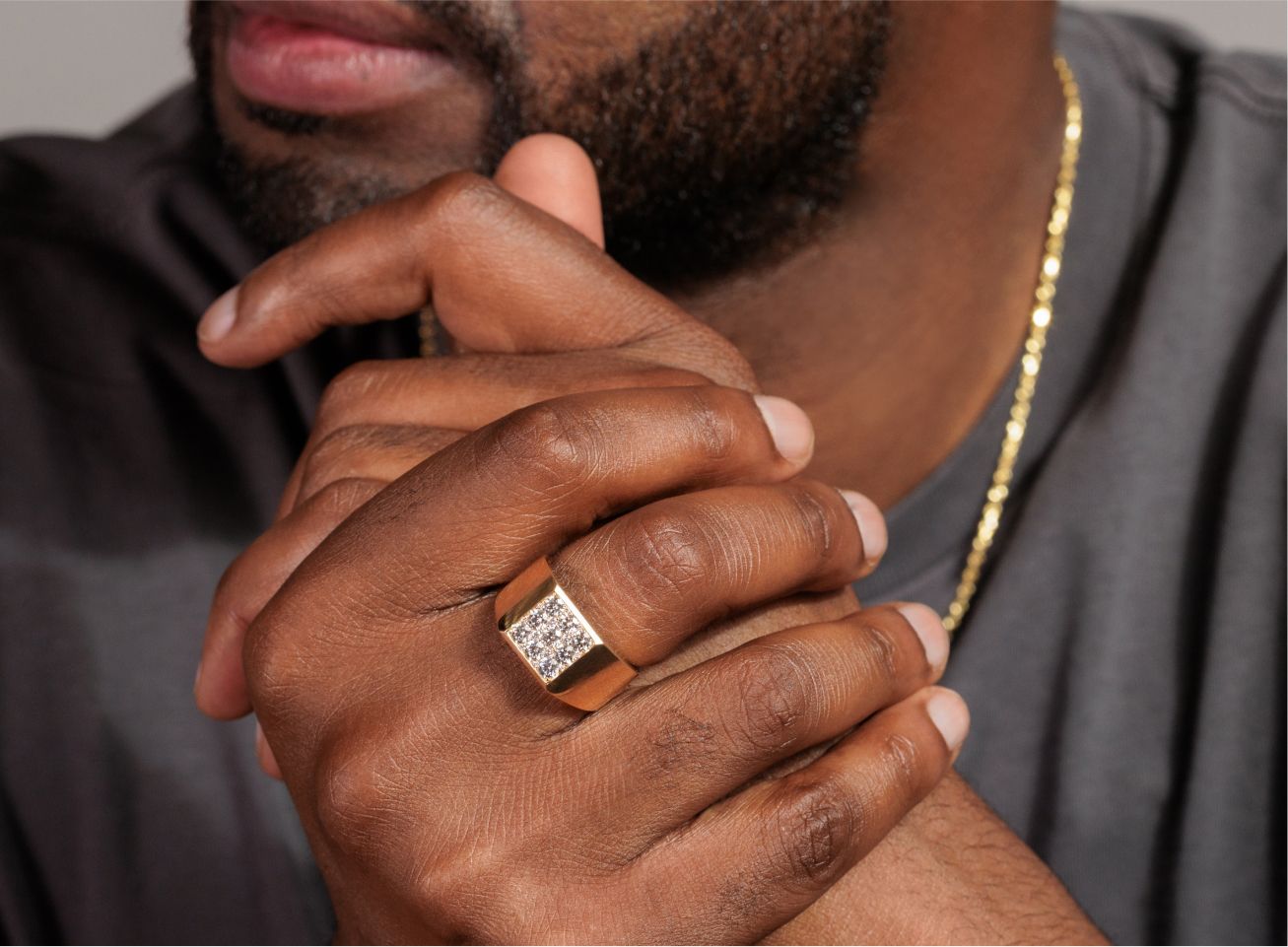 A man wearing a diamond ring and gold chain