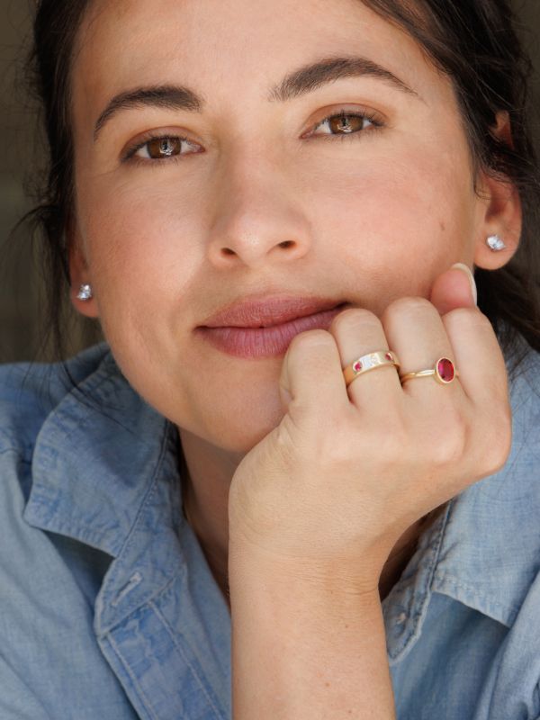 A woman wearing gemstone studs and fashion rings