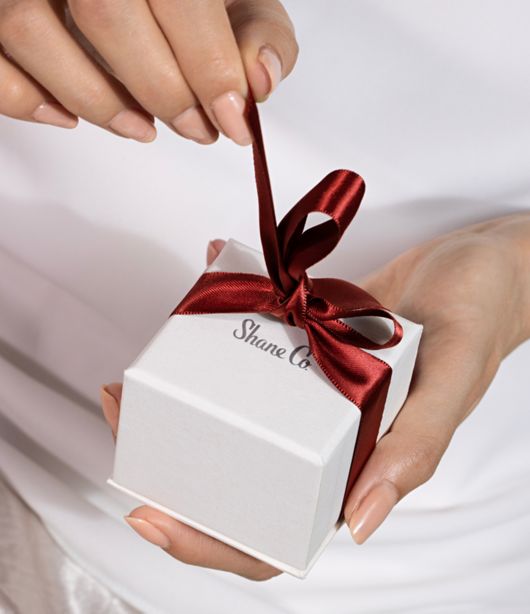 A woman opening a Shane Co gift box